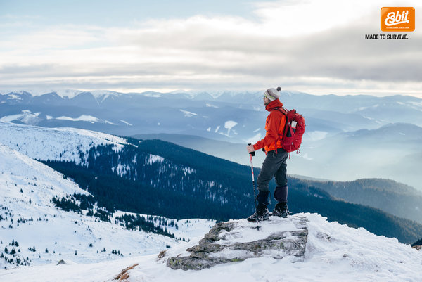 Mit einer Esbit Thermoskanne in der Rucksackseitentasche steht ein Wanderer auf dem Berggipfel.